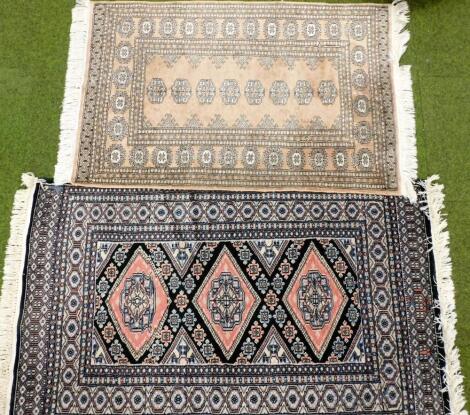 A Caucasian green and pink ground rug, decorated with three central medallions, within repeating floral borders, 90cm x 144cm, and a pink ground rug, decorated with a central row of medallions, within repeating borders of medallions and floral motifs, 80c