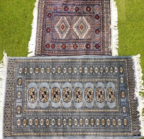 A Caucasian blue ground rug, decorated with a central row of lozenges within repeating floral borders, 77cm x 127cm, and a prayer rug decorated with two lozenges within repeating floral borders, 63cm x 80cm. (2)