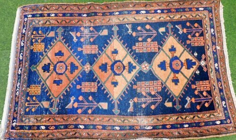 A Caucasian blue ground rug, decorated with three lozenge shaped medallions, trees and birds, within repeating borders of botehs, 180cm x 117cm.