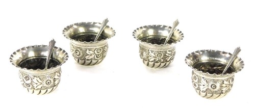 A set of George V silver salts and spoons, each with a flared rim and embossed floral design, London 1924, comprising four bowls and four spoons, in fitted case, 2¾oz.