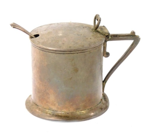A Victorian silver mustard pot, with a shaped thumb piece clasp on plain body with a buckle crest, London 1889, with a later spoon and blue glass liner, 4½oz.