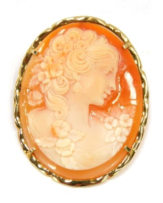 A shell cameo brooch, of a neo-classical design female with curled hair and flowers, in a flared gold frame, yellow metal, marked 585, 3.5cm x 2.5cm, 5.7g all in.