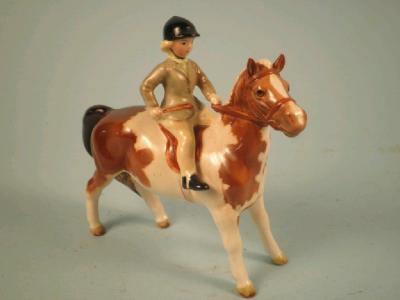 A Beswick figure of a young girl riding a skewbald pony