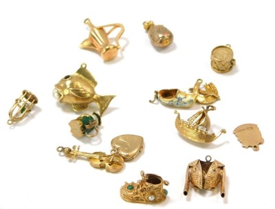 A group of 9ct gold charms, comprising fish with pearl, money bag, bird cage, ship, drum, bullfighting suit, jug, two shoes, Toby jug with enamel detail, heart shaped locket, and crest for Ashton-Under-Lyme, 36.7g all in.