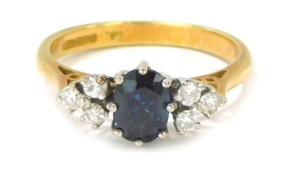 An 18ct gold sapphire and diamond dress ring, the oval cut sapphire in eight claw setting, flanked by three round brilliant cut tiny diamonds, size N½, 3.9g all in.