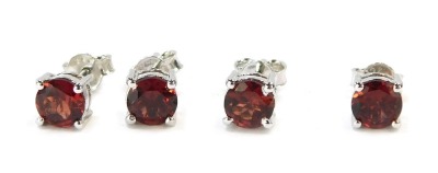 Two pairs of stud earrings, each in white metal baskets, stamped 925, set with red stone, 4.2g all in.