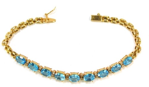 A blue zircon and diamond set line bracelet, set with nine oval cut blue zircons and twelve tiny diamonds, in yellow metal stamped 750, 18cm long, 14.7g all in.