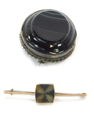 Two brooches, comprising a brown agate oval faceted brooch, in a white metal twist design frame with single pin back, and a bar brooch set with square central design with three leaf clover embedded stone, yellow metal bar stamped 9ct, 4.5cm wide, 3g all i