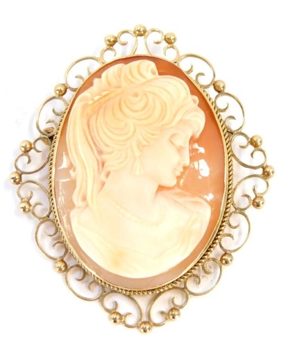 A late 19thC shell cameo brooch, depicting a maiden in flowing dress, quarter profile, with scroll outer border and single pin back, yellow metal, unmarked, 5.5cm x 4cm, 1.4g all in.