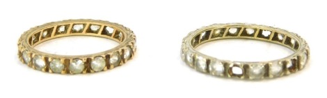 Two eternity rings, each set with CZ stones, white and yellow metal each stamped 9ct, ring size N and N½, 2g all in. (2)