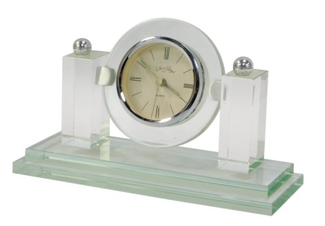 A Lloyd quartz mantel clock, with 6cm diameter, Roman numeric face, flanked by brass columns on a stepped rectangular base.