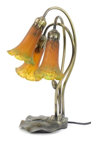 An Art Nouveau style table lamp, set with three trumpet stems in amber coloured glass, on an entwined metal stem and leaf base, 41cm high.