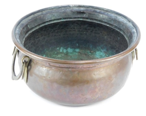 A late 19thC hammered copper bowl, with brass horseshoe handles, 32cm diameter.