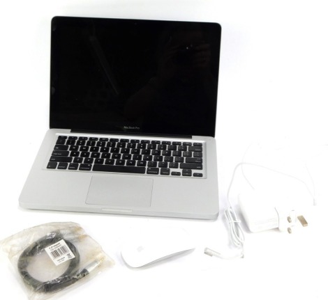 An Apple Mac Book Pro, with charger cable and wireless mouse.