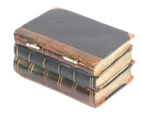 A ceramic trinket box, formed as three books and later painted, 15cm high, 11cm wide, 9cm deep.