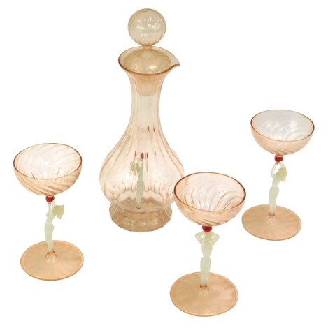 A Venetian pink glass decanter and stopper, the interior set with a female figure and three matching glasses.