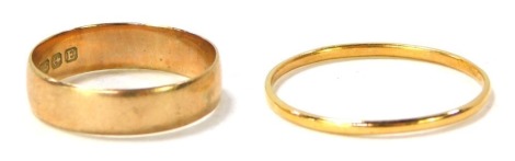 Two wedding bands, comprising a 9ct gold plain design wedding band, size L½, 1.6g, and a thin yellow metal wedding band, unmarked, 1.1g. (2)