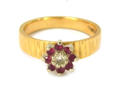 An 18ct gold garnet and diamond floral cluster ring, the cluster set with central diamonds surrounded by garnets, on bark effect band, size O½, 5g all in.