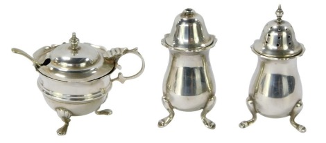 A George V silver three piece cruet, comprising salt and pepper, mustard and spoon, two pieces, Chester 1909, and another London 1914, one blue glass liner, 3½oz.