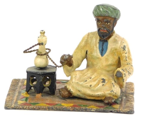 A Bergman style cold painted spelter figure, seated on a Persian carpet, with oil lamp, 7cm high, 8cm wide. (AF)