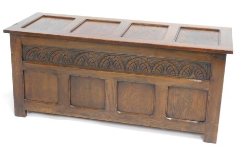 An oak coffer, with four panel top and carved scroll panel, on stiles, 52cm high, 122cm wide, 46cm deep.