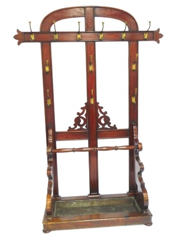 A Victorian mahogany hall stand, with arched top with applied brass hooks, umbrella well base on bun feet, 251cm high, 150cm wide, 55cm deep.
