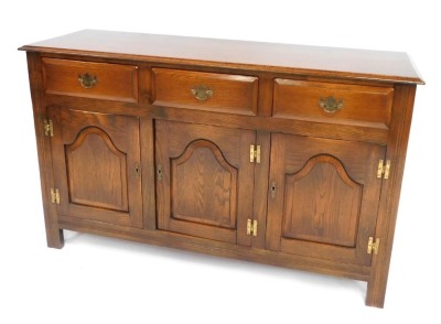 An oak sideboard, with three drawers and three cupboard doors on styles, 83cm high, 135cm wide, 43cm deep.