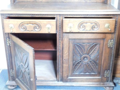 A carved oak dresser, the raised back with fan detail above two drawers and two cupboards, on bun feet, 88cm high, 104cm wide, 54cm deep. - 2