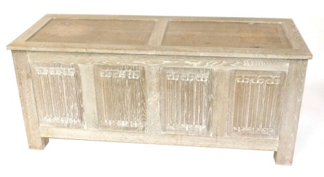 A limed oak blanket box, with two paneled top above three carved panels on stile supports, in the manner of Heals, 67cm high, 150cm wide, 56cm deep. (AF)