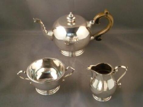 A silver three piece tea service comprising a bullet shaped teapot with ebonised handle