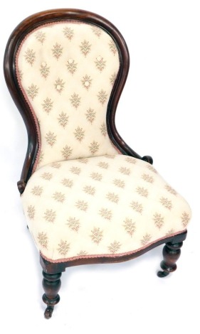 A Victorian mahogany spoon back nursing chair, on cream floral upholstery, with pink ribbon surround, 100cm high, 60cm wide.