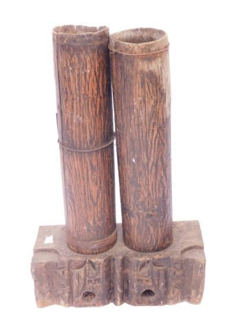 An African tribal drum set, with two drums on a block carved base, with iron bands, 96cm high, 64cm wide, 24cm deep.