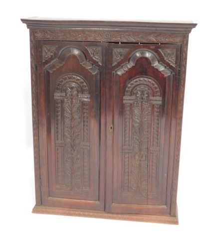 An oak cabinet, with a carved border and two paneled doors, with a shaped cornice, and brass key lock, 125cm high, 97cm wide, 26cm deep.