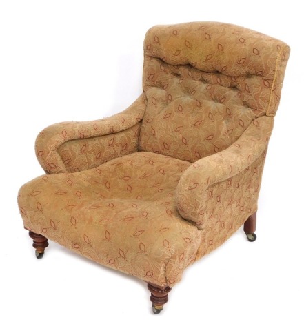 A Victorian armchair, in the manner of Howard with shaped arms and a button back, with walnut feet on castors, 84cm high, 73cm wide, 72cm deep.