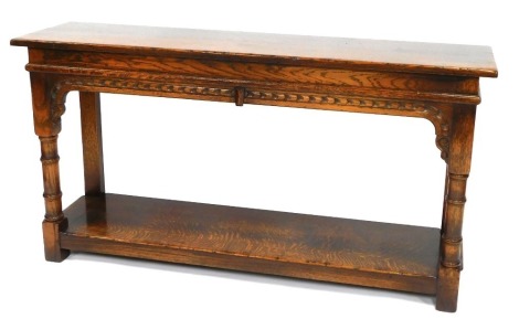 An early 20thC oak hall table, with rectangular top and lower tier shelf, with carved detail, 71cm high, 125cm wide, 39cm deep.