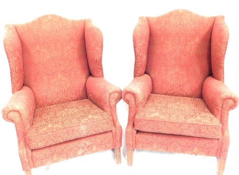 A pair of mahogany wingback armchairs, each with a red and gold leaf upholstery, 106cm high, 65cm wide, 61cm deep. The upholstery in this lot does not comply with the 1988 (Fire & Fire Furnishing) Regulations, unless sold to a known exporter or upholstere