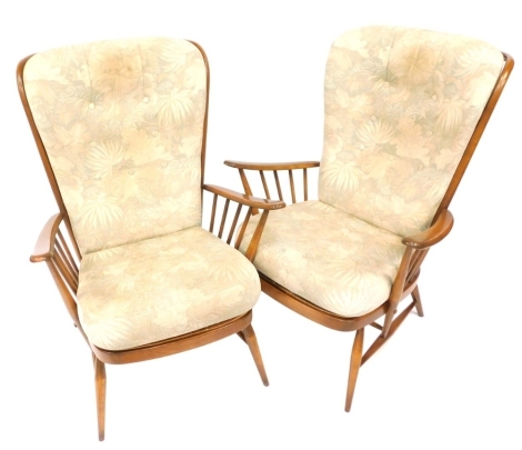 A pair of Ercol armchairs, each with a shaped stick back and arms, with two cushioned seats, 102cm high, 75cm wide, 52cm deep. The upholstery in this lot does not comply with the 1988 (Fire & Fire Furnishing) Regulations, unless sold to a known exporter 