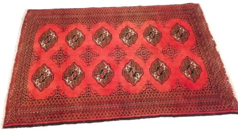 An Afghan or Pakistani rug, with two rows of guls on a red ground, 140cm x 100cm.