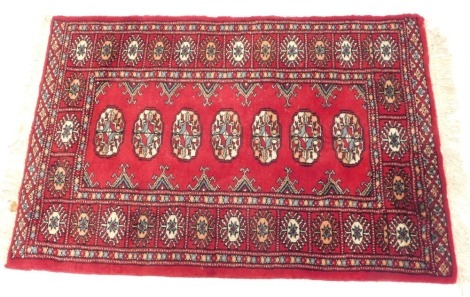 An Afghan or Pakistani rug, with seven guls to the centre, with similar design to the outer border, 90cm x 66cm.