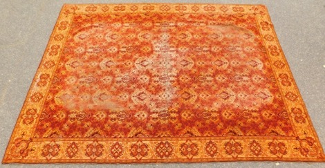 An Oriental design rug, on an orange ground with medallions and flowers, and spotted border, 210cm x 153cm.