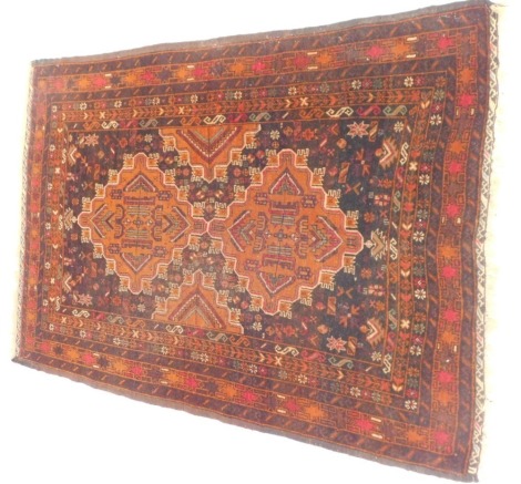 A Persian rug, on a brown and burnt orange ground, with two central medallions and geometric border, 145cm x 100cm.