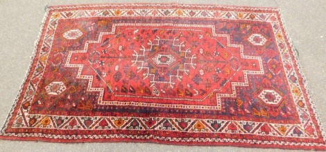 An Eastern style rug, on a red cream and black ground, with central medallions, 224cm x 140cm.