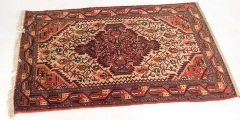 A Persian rug, on a red and cream ground, with large central medallion, and multi coloured borders, 125cm x 75cm.