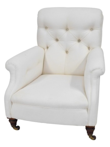 A Victorian button back low armchair, deep seated with turned walnut legs with brass and ceramic castors, upholstered in cream, 90cm high.