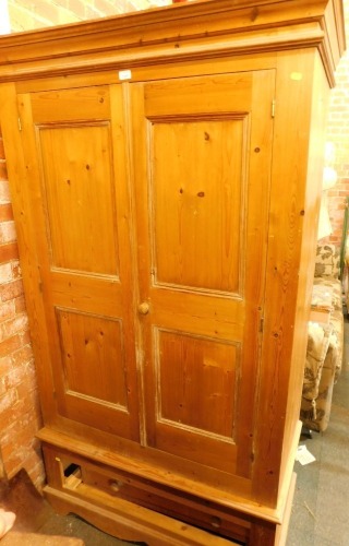 A pine two door wardrobe, the two paneled doors above single drawer with moulded cornice top, on bracket feet, 195cm high, 115cm wide, 58cm deep.