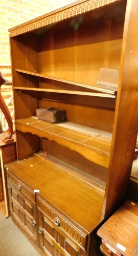 A dark oak dresser, with shelved top above two cupboard and two drawer base, with buckle band supports.