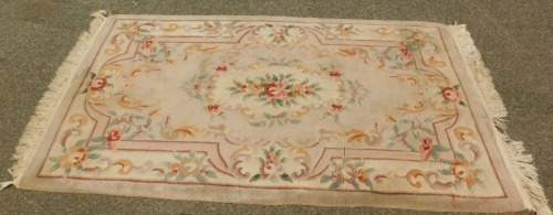 A Chinese wool cut rug, on a cream ground with pink border and roses.