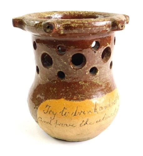 A West Country two coloured stoneware puzzle jug, with pierced top, the body with the motto Try To Drink And Not To Spill And Prove The Upmost Of Your Will, 17cm high.