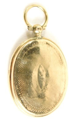 A heart locket, with ring top and oval body, engine turned with central vacant cartouche and plain interior, yellow metal unmarked, 4cm high.