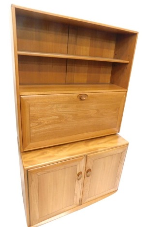 An Ercol light coloured elm dresser, the raised back with two shelves above a fall front section, the base with two doors, each with turned and shaped handles on castors, 168cm high, 91cm wide.